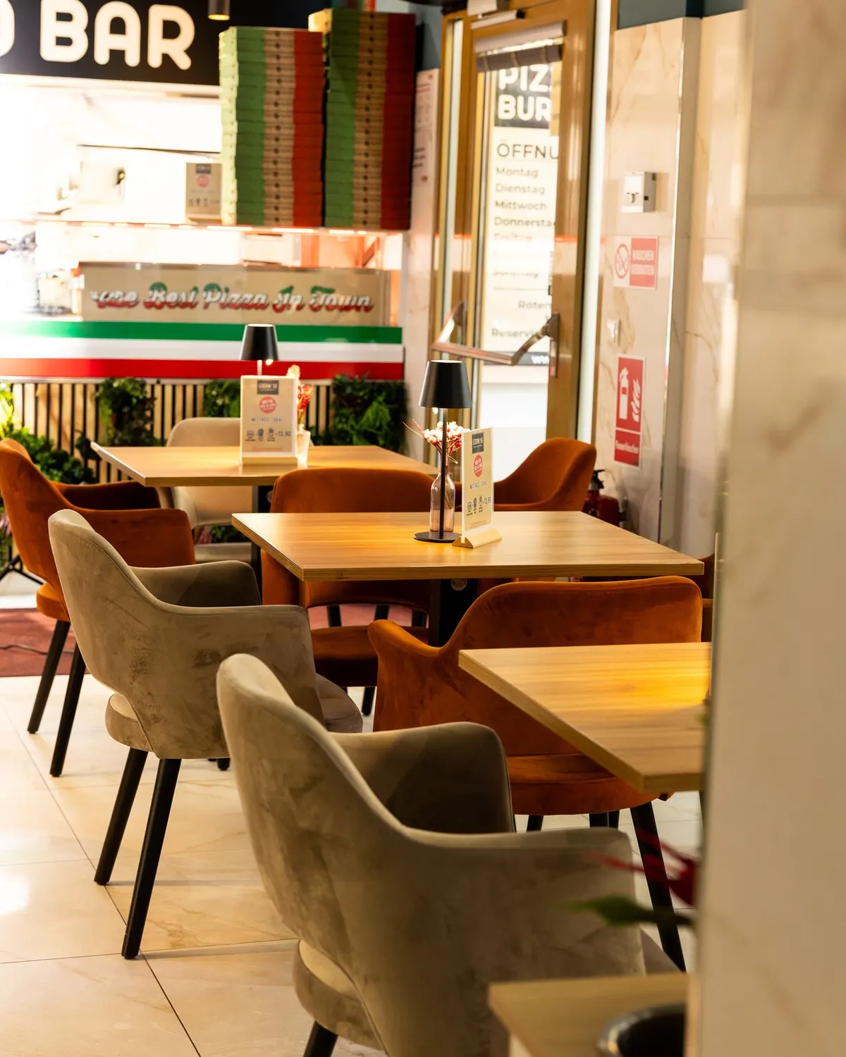 Gastraum des STERN*16 in der Rotensterngasse 16 mit Holztischen, Samtstühlen und Pizza-Theke