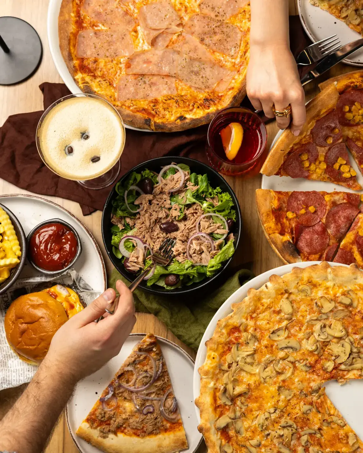 Table with ham pizza, diavola, funghi, tuna salad, burger and cocktails at STERN*16
