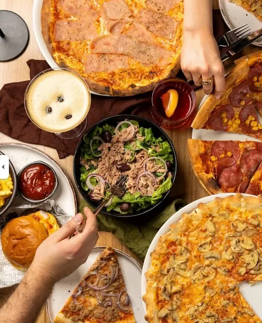 Gedeckter Tisch mit Pizza, Bowls und Getränken